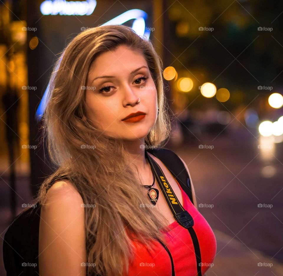 young blonde woman, arrested on the sidewalk, at night with camera strap around her neck