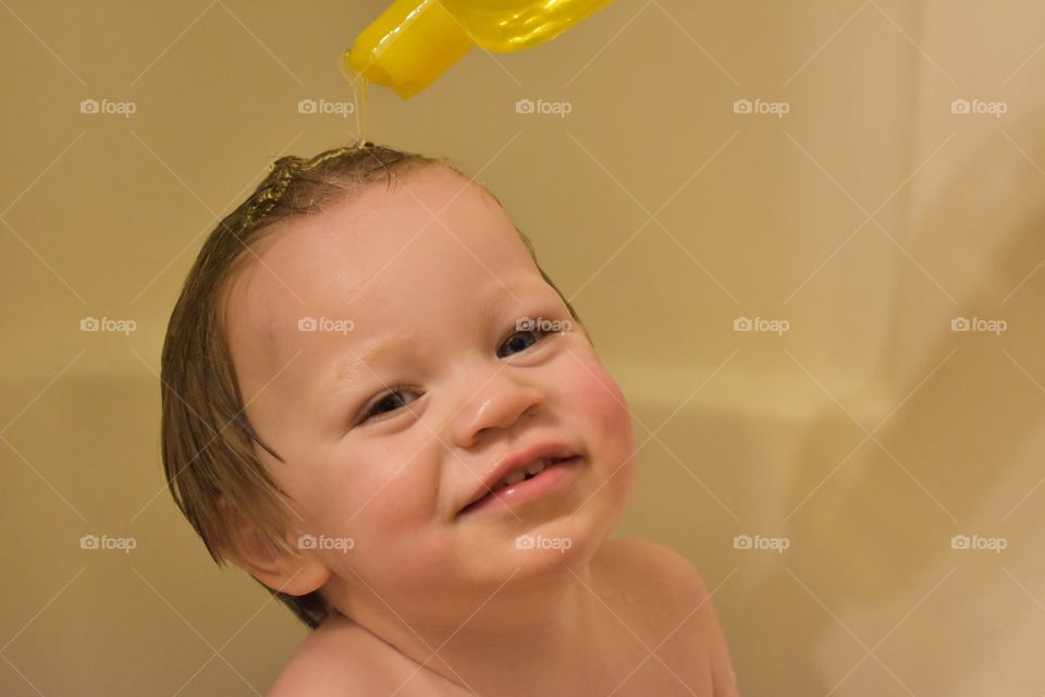 Cute toddler boy having fun playing in bath and washing his hair 