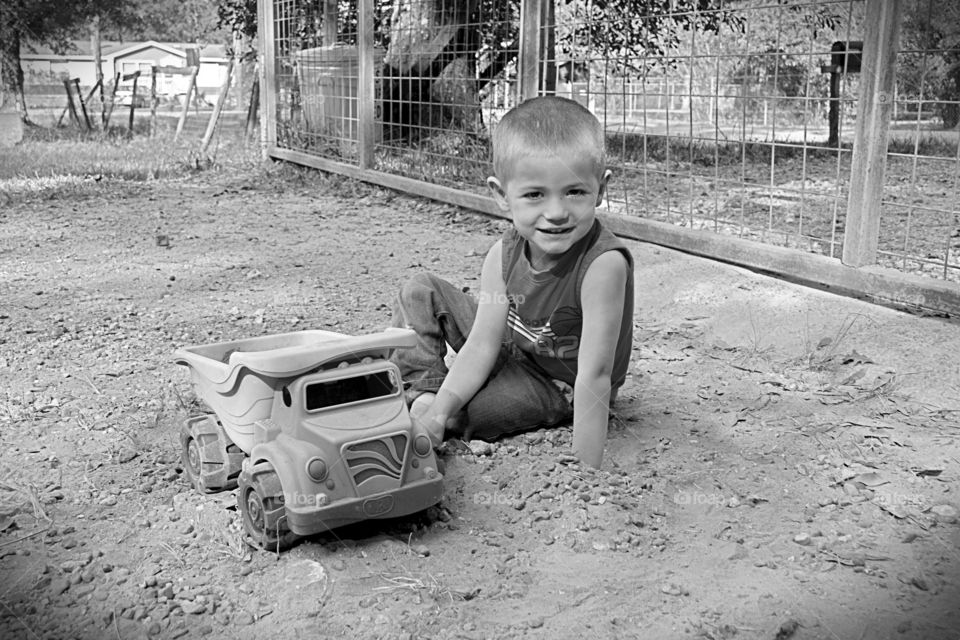 Grandson playing with dump truck in the driveway 