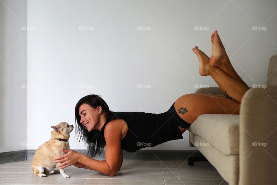 beautiful girl with her dog at home.  the girl has a beautiful tattoo on her ass
