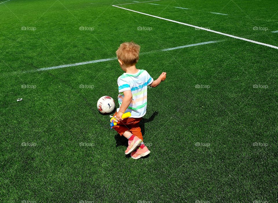 Little boy playing football on greeen field