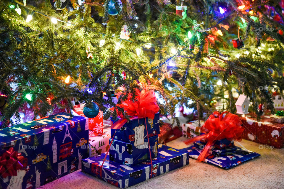 Wrapped Christmas presents sitting under a lit Christmas tree