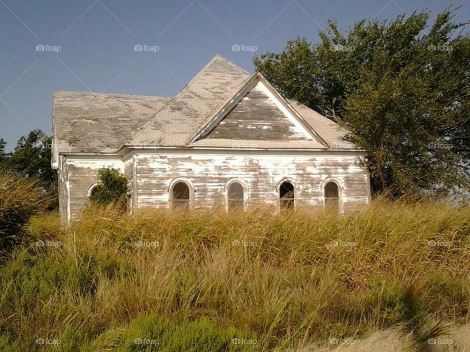 A Old Church that once stood very new.  There are no more services held here any more and the grass and weeds are waist tall. It is very old and the white paint has just about all peeled off.
