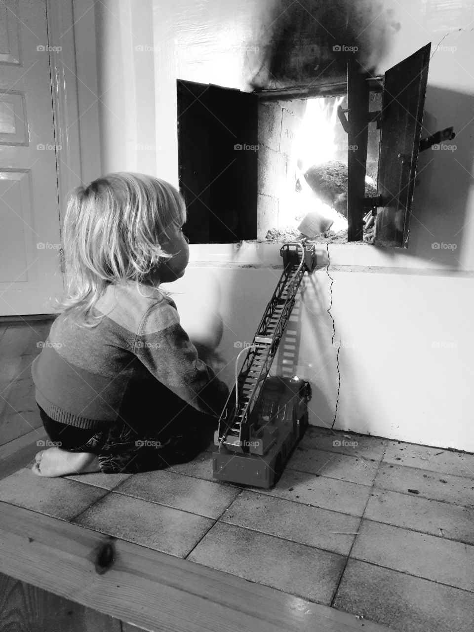 A young child estinguish the fire with a firetruck.