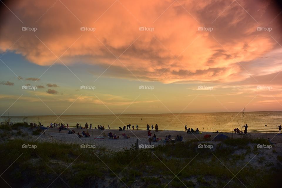 A crowded beach in Tampa bay, Florida watches a beautiful sunset and skyline.