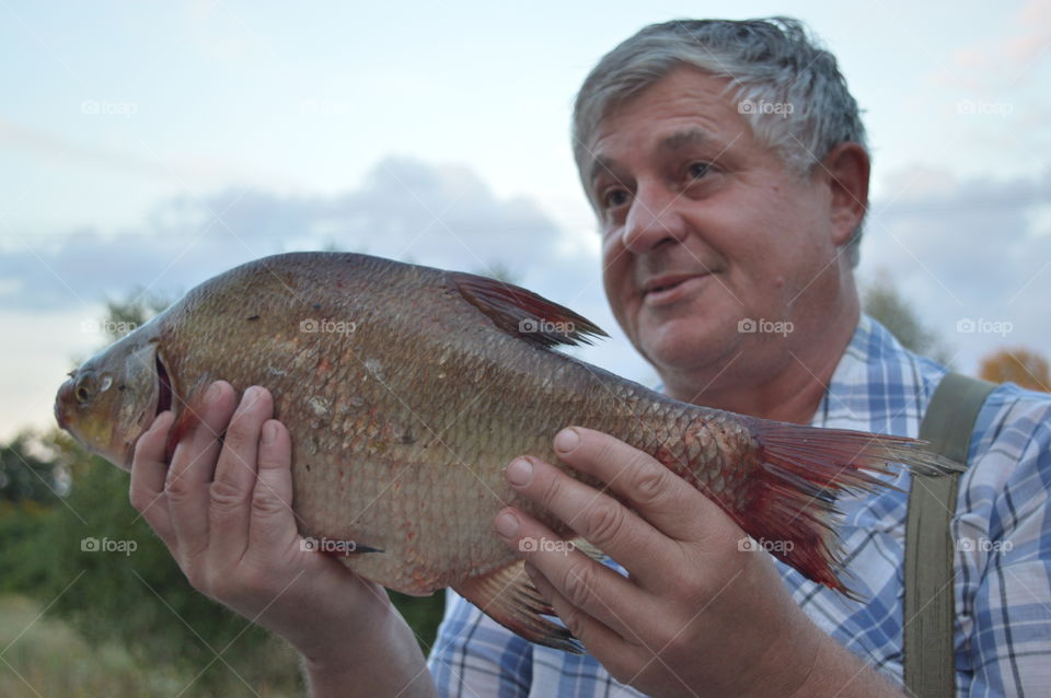 Close-up of a mature man holding dead fish in hand