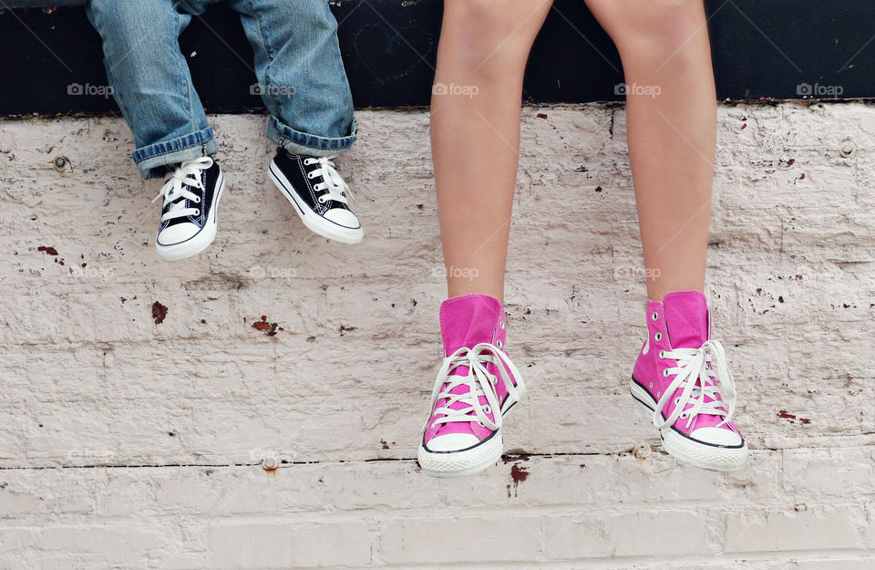 Low section of girl and child wearing shoes