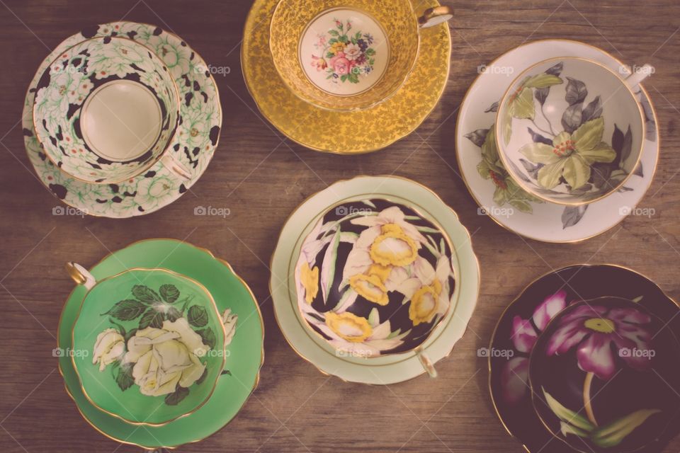 A collection of vintage china teacups on a wooden table