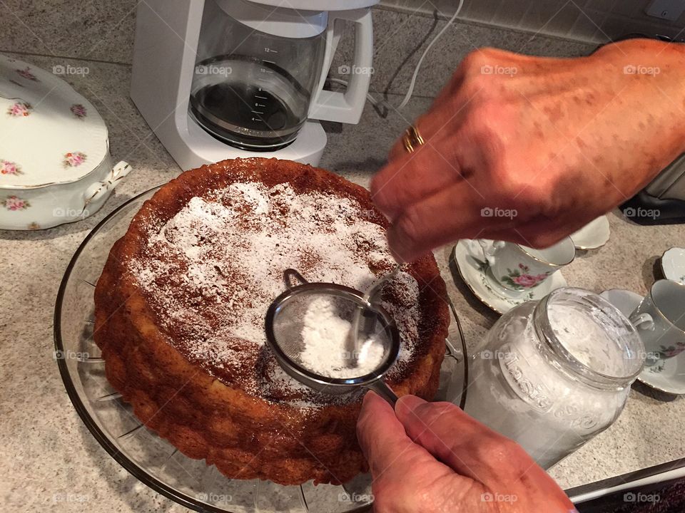 Experienced hands putting the finishing touch on a delicious homemade cake. 