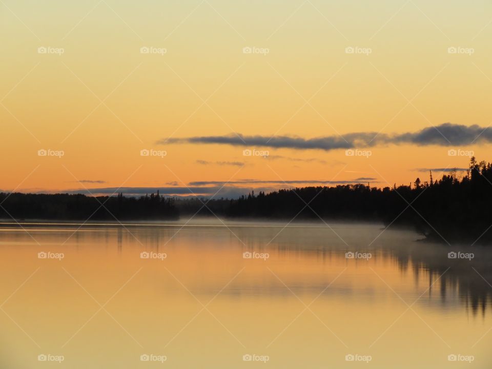 A the after glow of a foggy sunset reflected in Little Current River in northern Ontario, Canada.