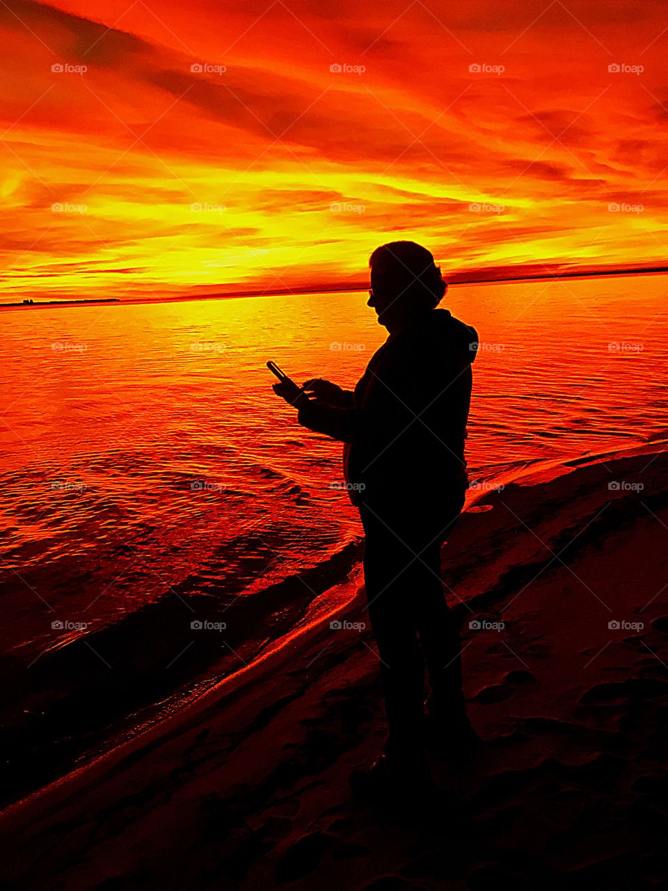 Photographing a woman taking sunset photos with her phone 