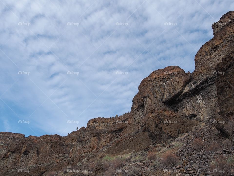 Detailed rock cliffs on a steep hill with nice blue skies in Central Oregon. 