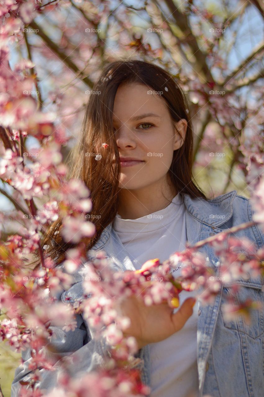 Girl standing under Pink cherry blossom tree.