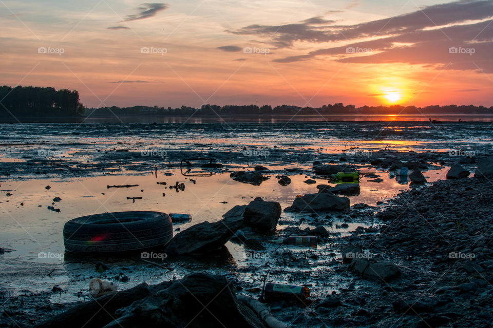 View of garbage in lake at sunset