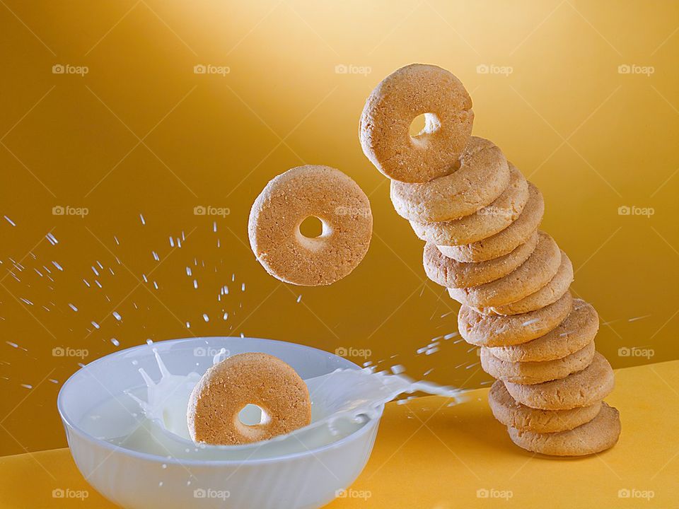 Cookies falling in a mug of milk