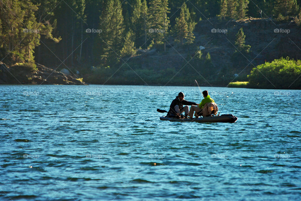Men in canoe fishing in lake during summer time