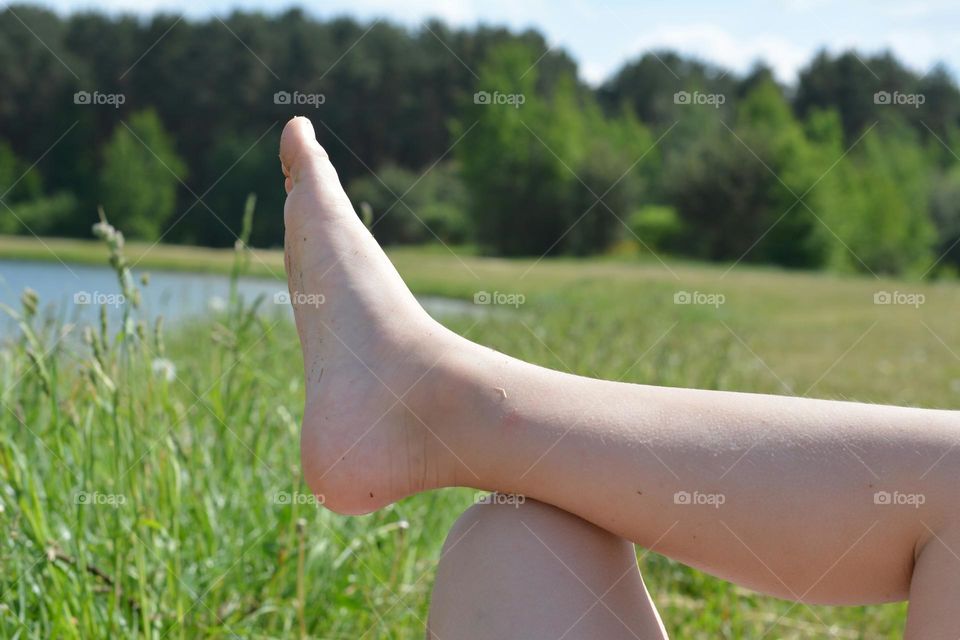 children legs resting on the green grass view from the ground