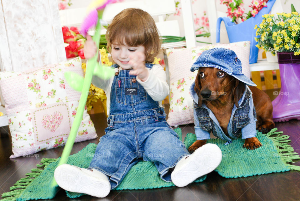 Cute boy sitting with puppy wearing cap