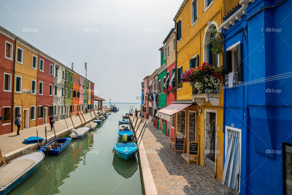 Boats anchored on canal by colorful houses