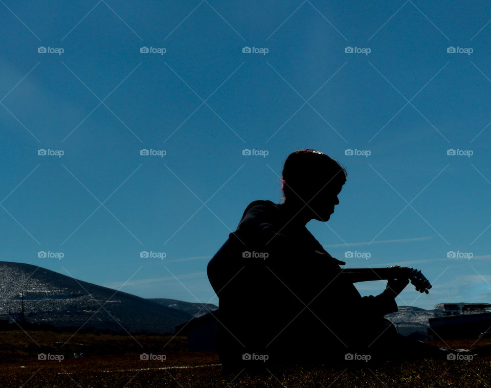 A silhouette of someone playing the guitar 