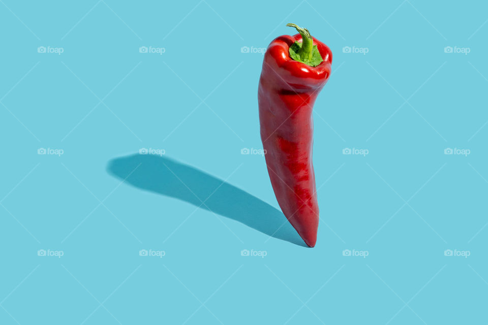 Red standing chilli pepper against blue background