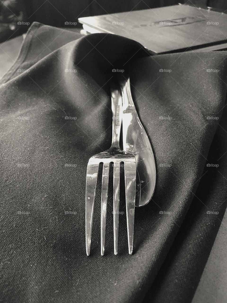 Simple place setting in black and white.  The shiny silver utensils contrast beautifully against the black napkin. 