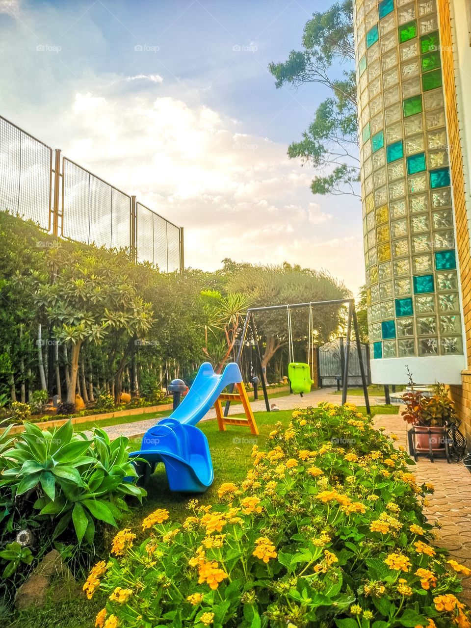 Colorful garden with a kids slide and swing.