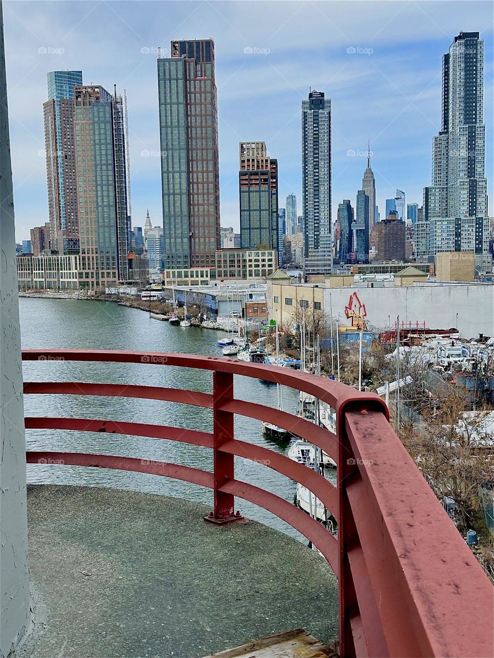 This is “Newtown Creek” seen from the central outpost of the “Pulaski Bridge” that connects “Greenpoint”, Bklyn to LIC, Queens. Across the waters of the “East River” we see “Manhattan” including the “Empire State Building”. 2024. Hypnotic Productions