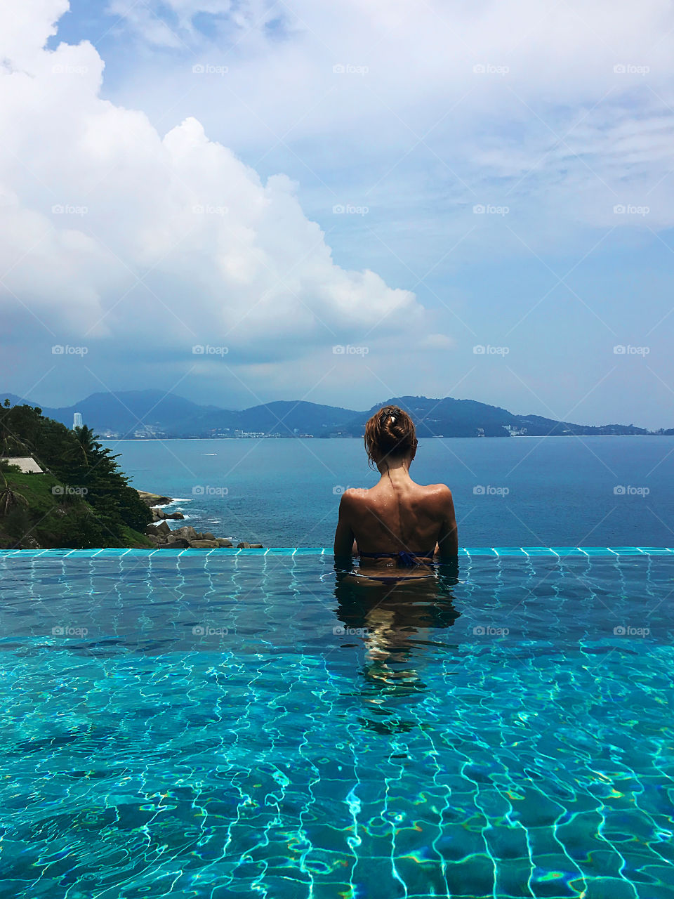 Enjoying tropical vacation in swimming pool above the sea 