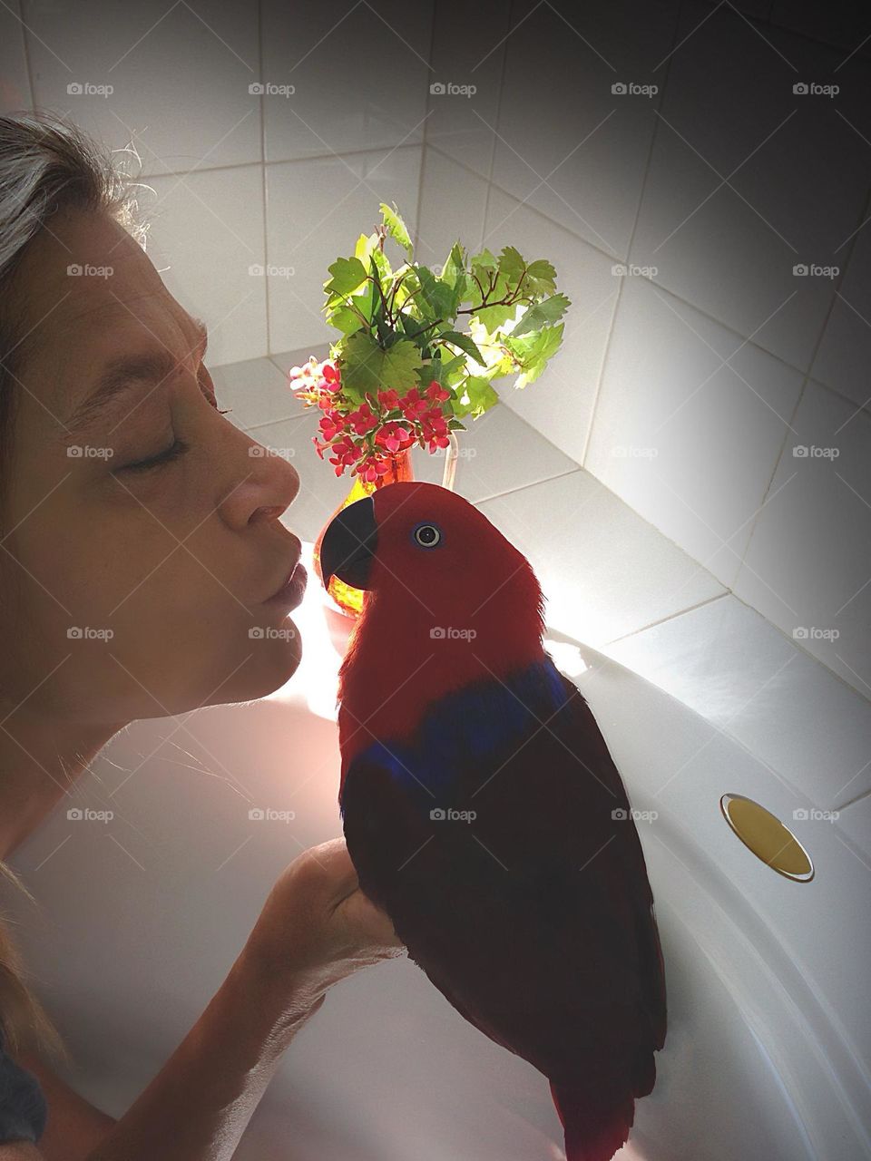 Woman kissing her beautiful parrot Sadie.
