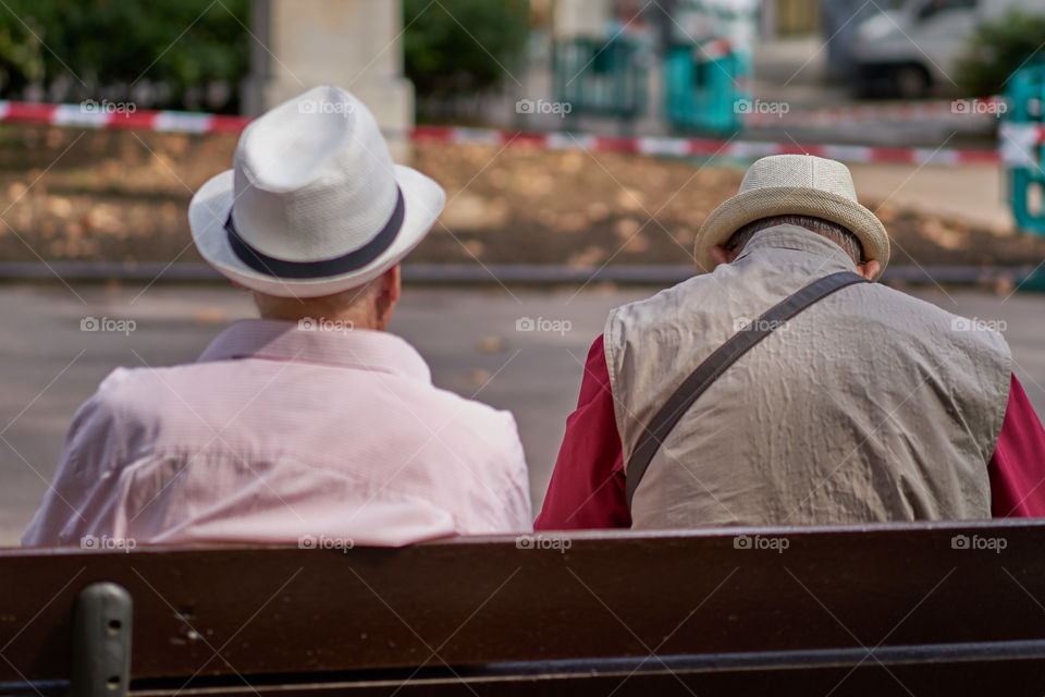 Elderly men with hat sitting in a street bench