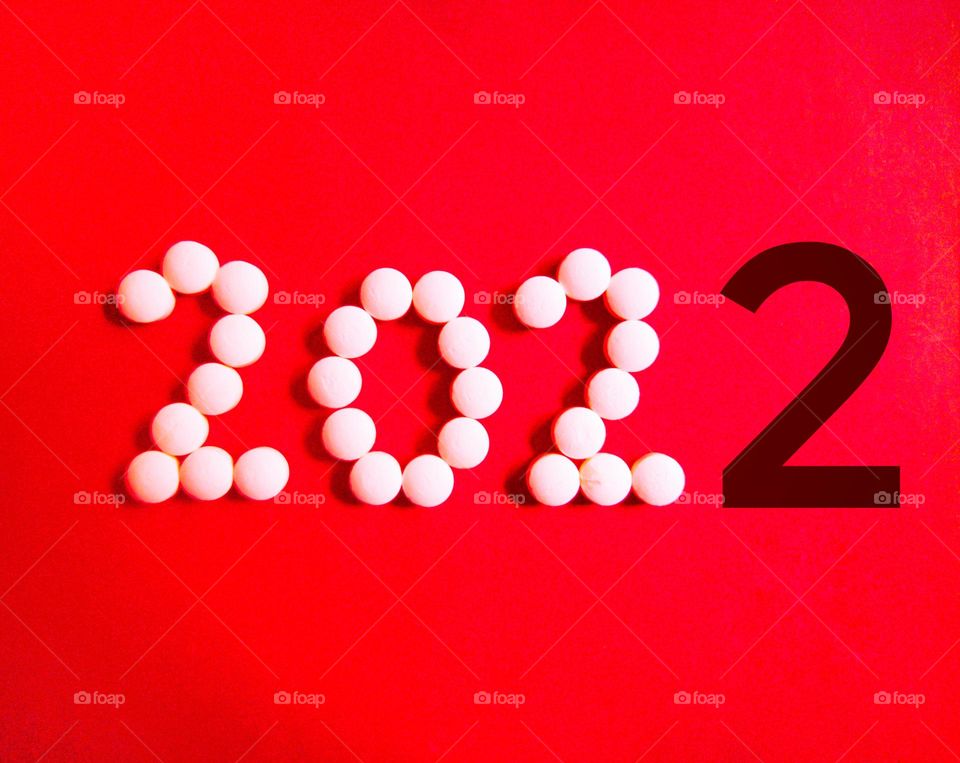 new year 2022 with white colour and last number 2 it's with black colour to distinguish ,  pills concept , red background