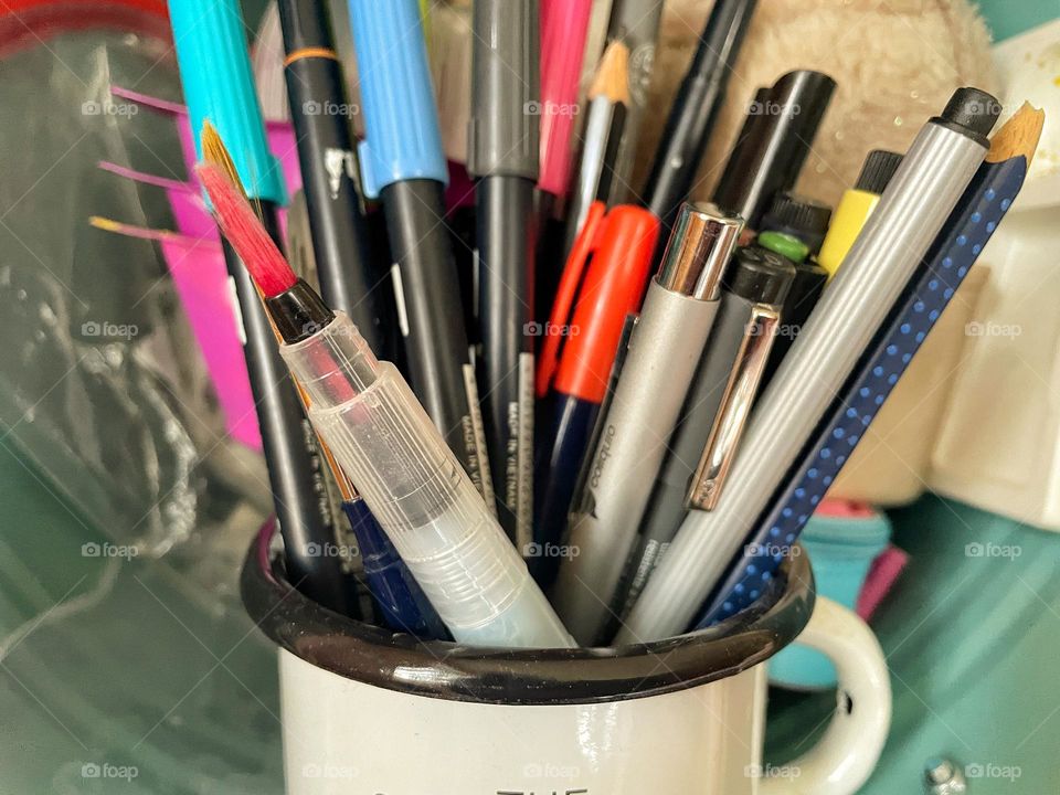 Close-up of many colorful pencils and brushes in the mug