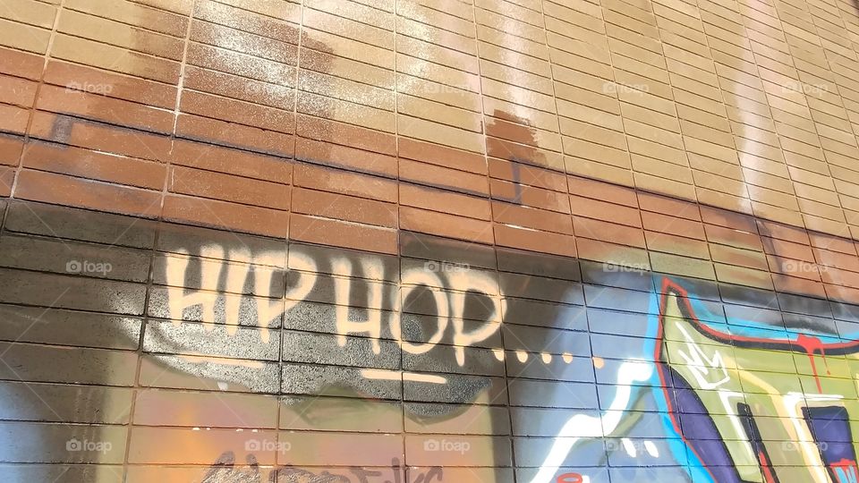 Hip-hop graffiti art on brick wall over mural art with buffed patches