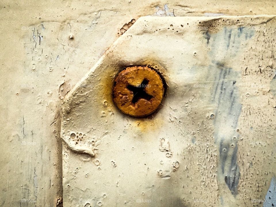Rusted screw in old wall with peeling paint grunge background image