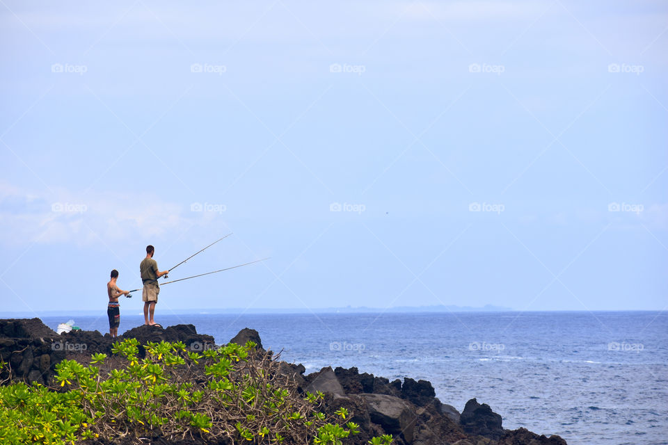 Fishing on a blue sky day along the lava sea cliffs on the east side of the Big Island of Hawaii.