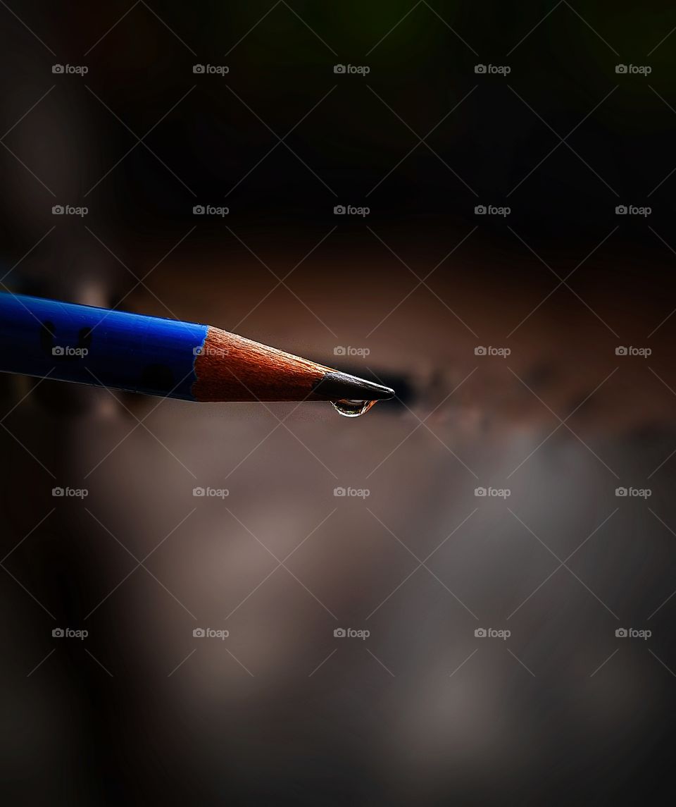 In this photo I focused on a blue pencil with a drop of water in the tip of the pencil