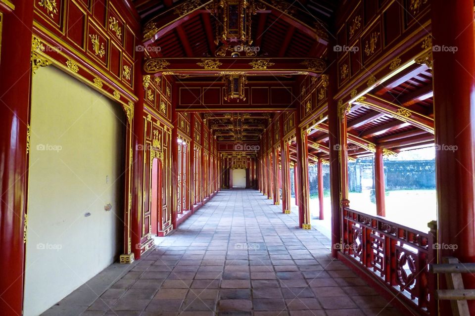 A passage for kings in old palaces , the pillars and things made of wood are painted red and a little yellow, the floor  is lined with red brick now they are old and worn a lot , on the left are the doors