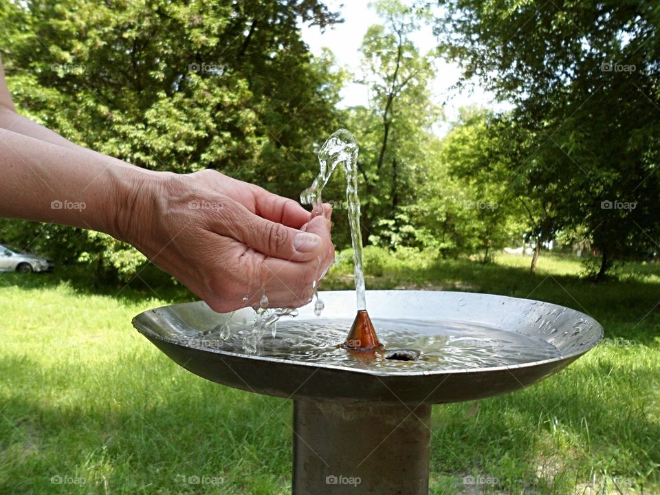 water flows into the hands of women from the fountain