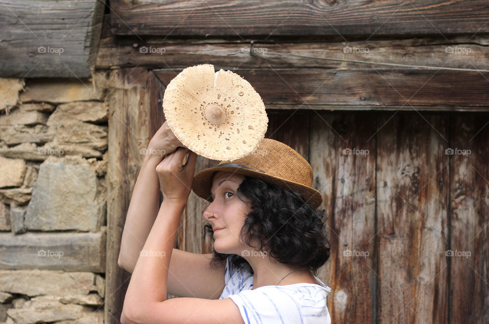 Young woman with summer hat holding a mushroom, countryside life