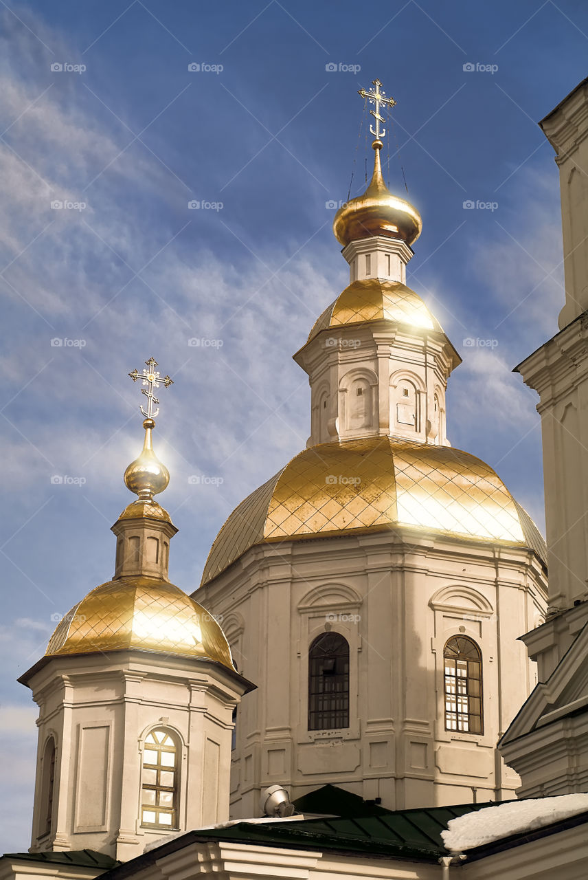 The rays of the rising sun are reflected in the domes of the Kazan Cathedral in Holy Trinity Seraphim-Diveevsky monastery (Russia, Diveevo) in the early spring morning against a blue sky covered with a cloudy pattern