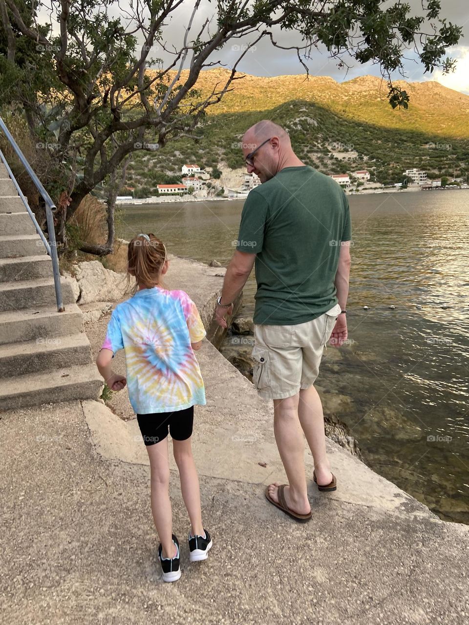 A father sharing a late afternoon walk by the sea with his daughter.