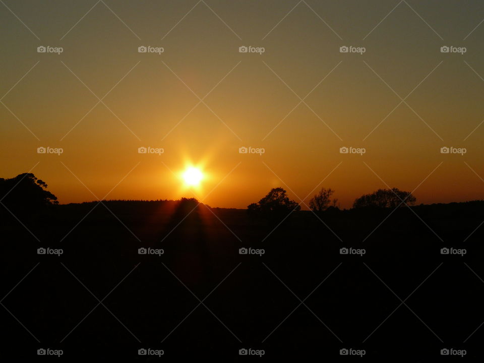 Beautiful sunset on the horizon in the countryside with bright orange yellow red and grey blue colours vibrant sky scene