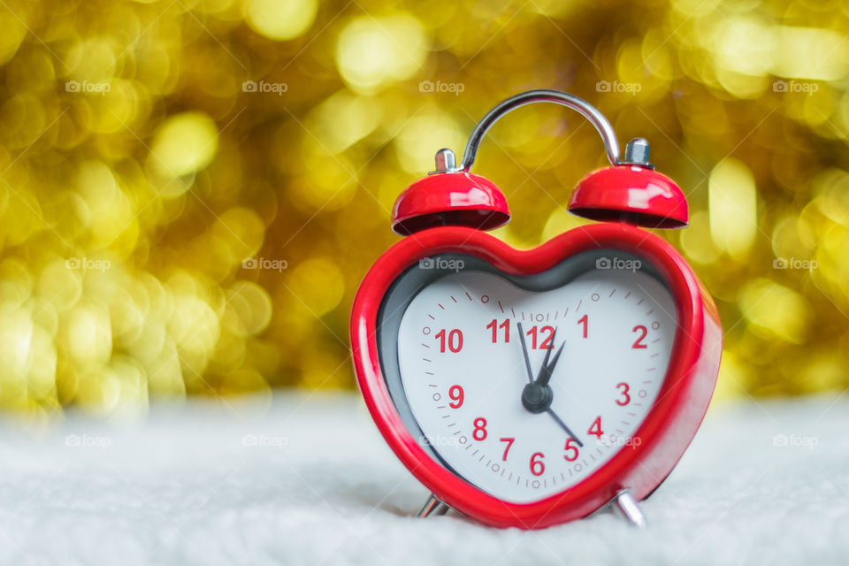 Red clock on blurred golden background 