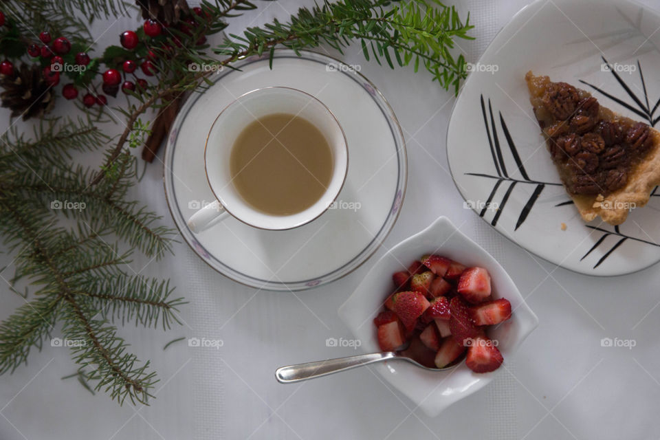 Tea, strawberries and pecan pie in a festive flat lay. Teapot in shot on white table cloth
