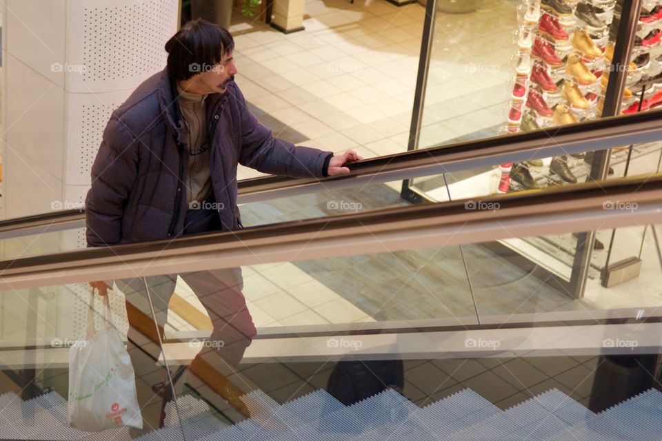 Man on escalator in shopping center