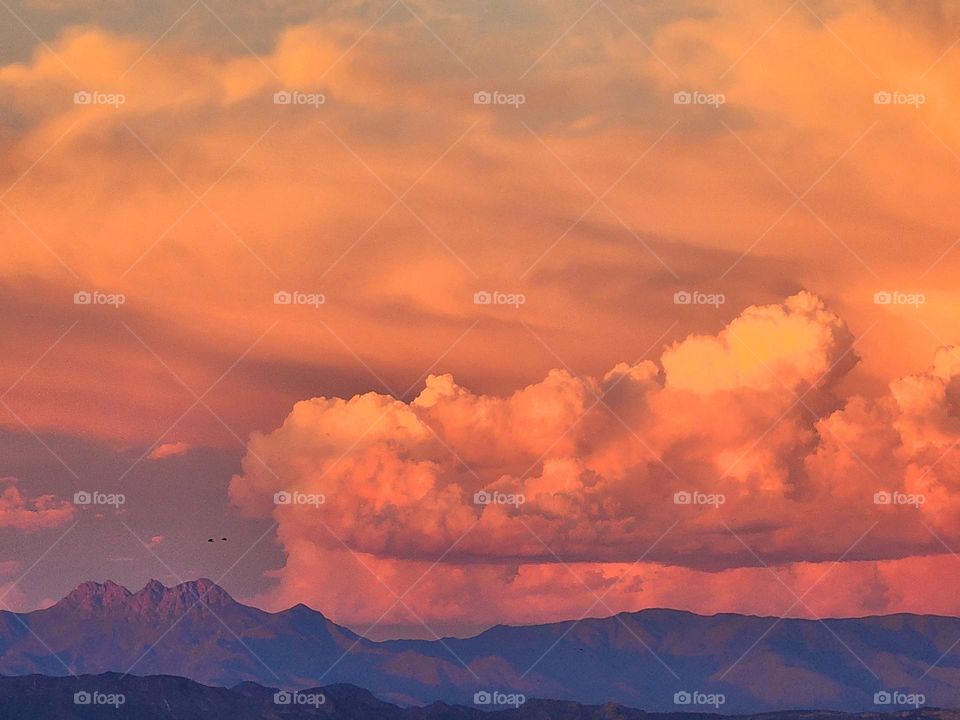 Sunset makes the clouds behind Four Peaks glow in spectacular shades of orange and yellow as a storm system moves across the range
