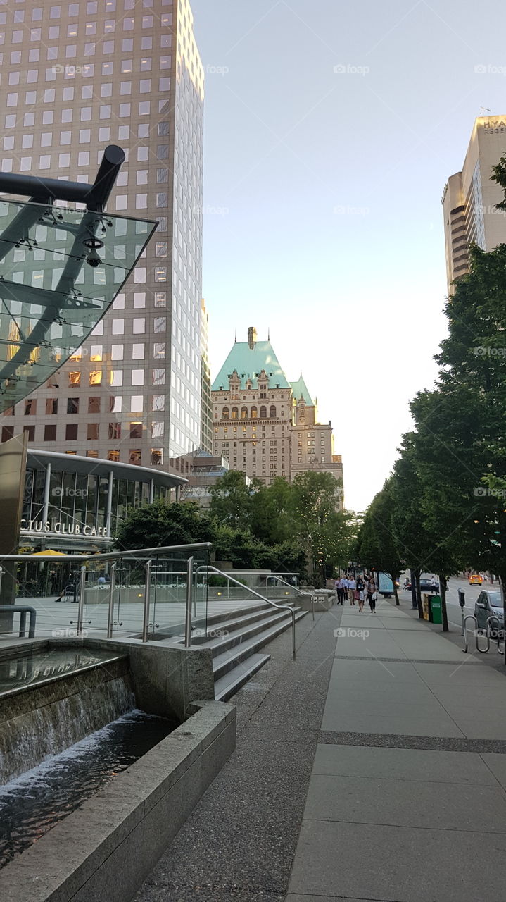 downtown city street scene with modern tall buildings and older architecture at sunset