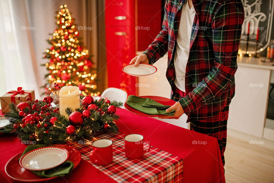 man sets a beautiful decorated winter table for a festive dinner.  Merry Christmas and Happy New Year.