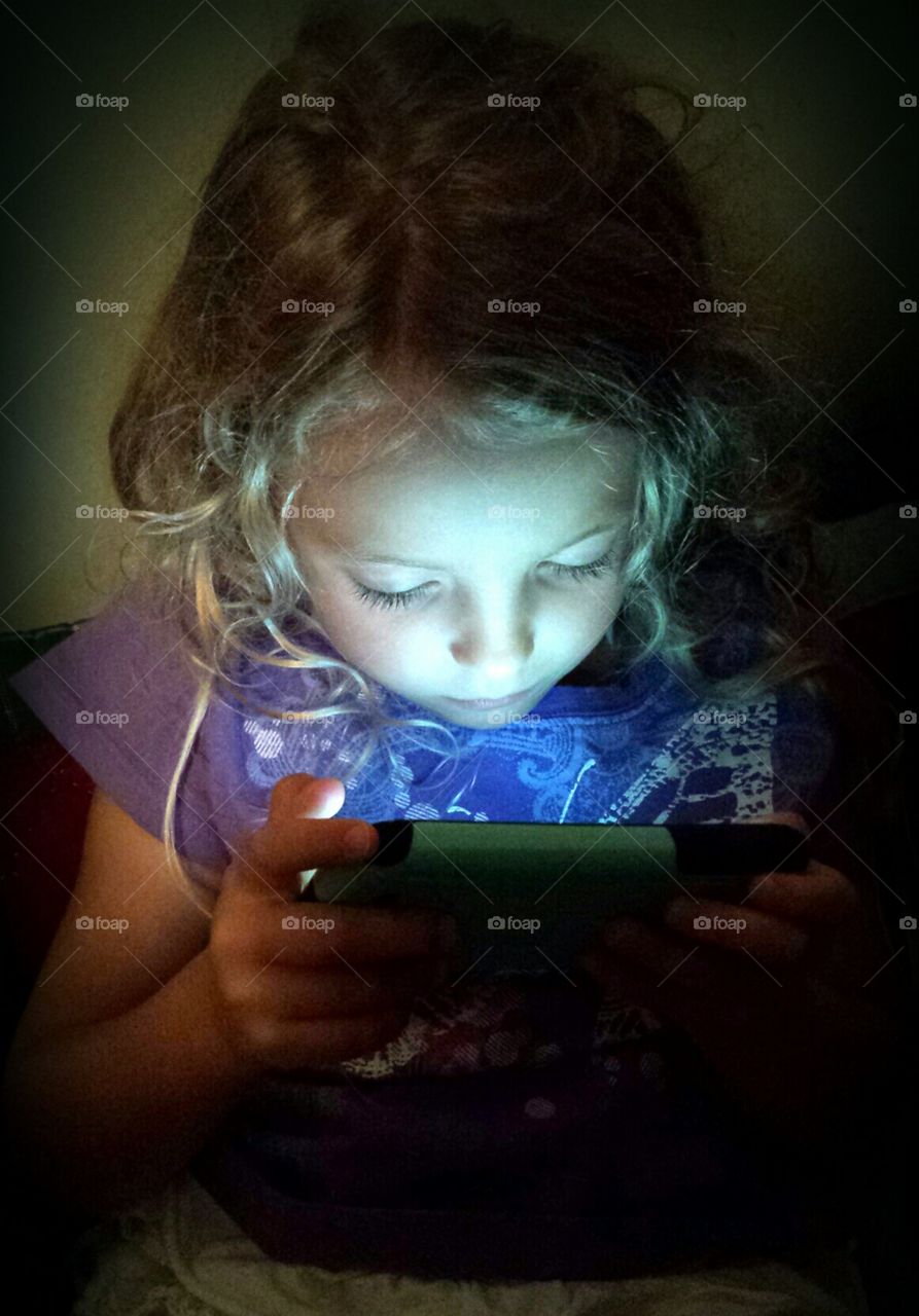 Occupied. Girl playing a video game on a cell phone.